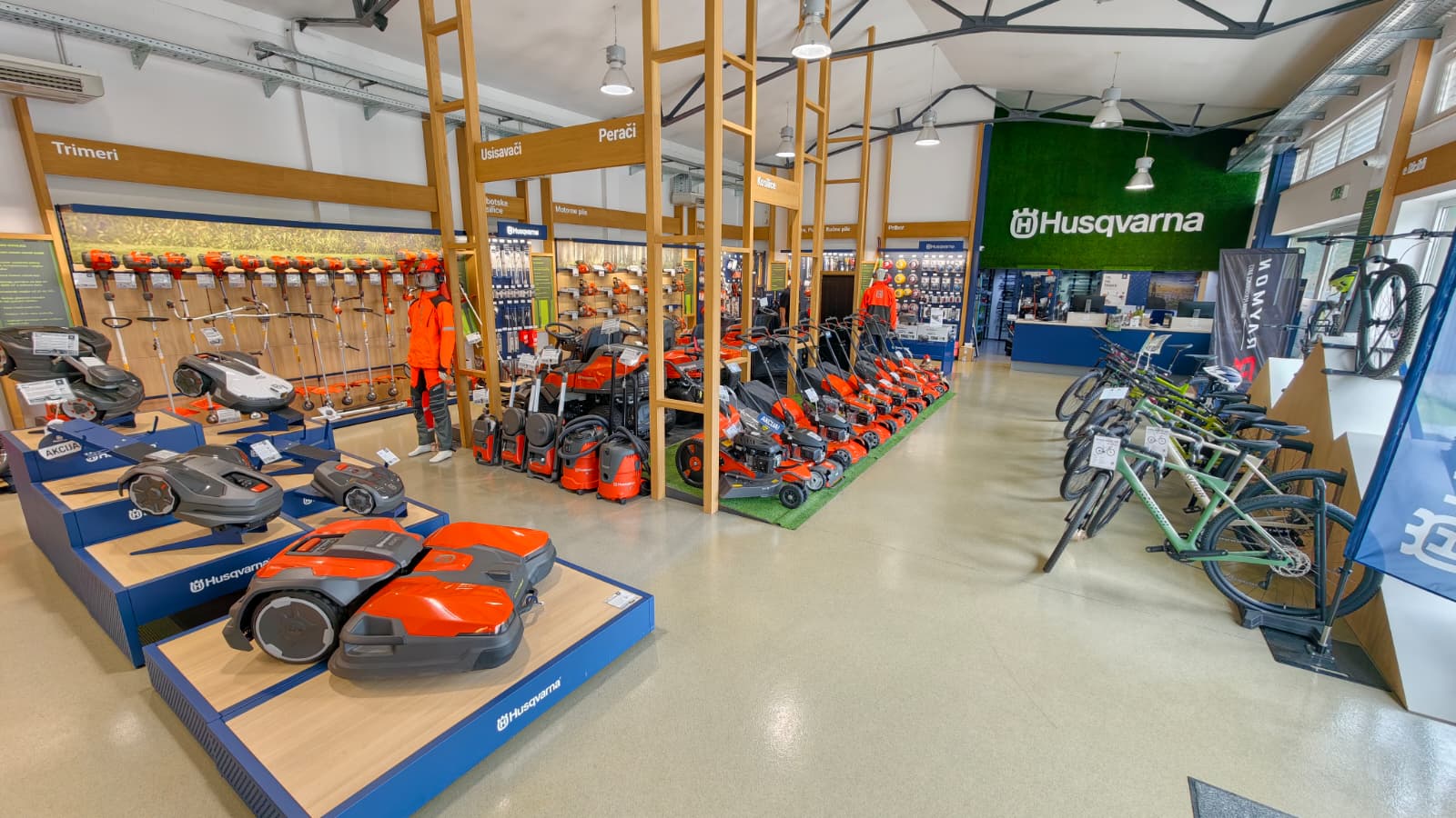 Unutrašnjost trgovine Pile i Vile s izloženim Husqvarna kosilicama, robotima i biciklima